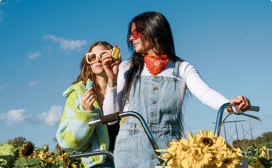 Friends enjoying Holiday H-Bar all-in-one THC vapes outdoors in a sunflower field